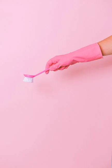 Vue de côté d’un jeune employé tenant une pile de serviettes blanches dans la salle de bain d’un hôtel de luxe